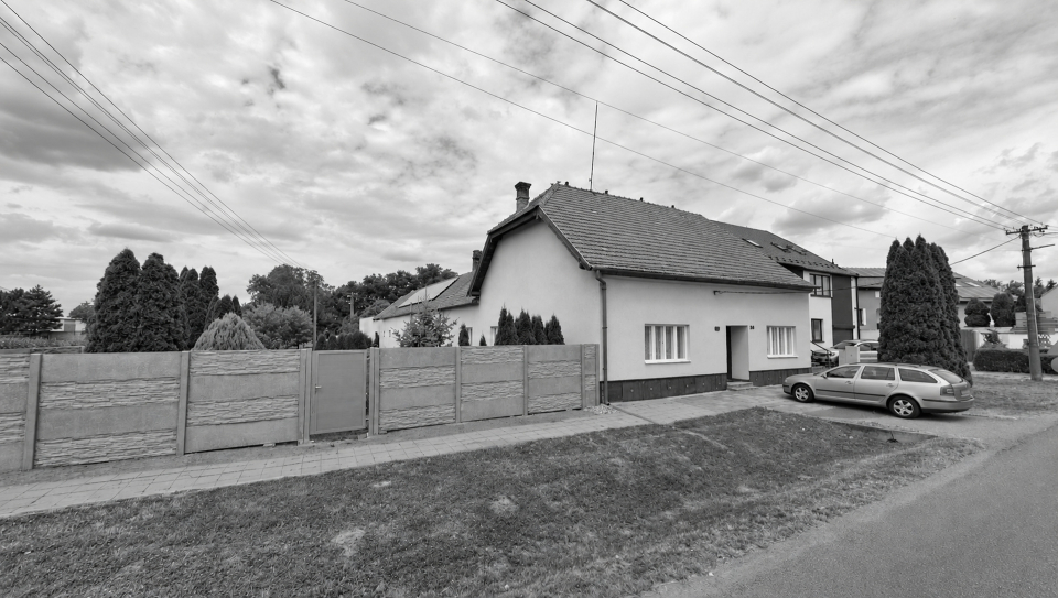 Černobílá fotografie původní venkovské usedlosti před přestavbou.